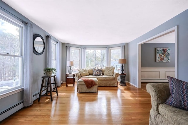 living area with light wood-style flooring and a baseboard heating unit