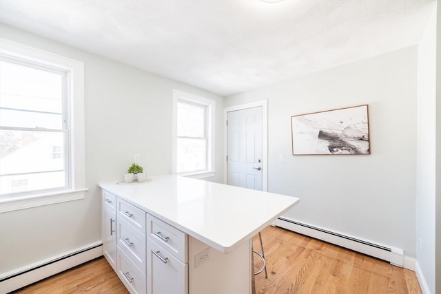 17 Norcross St Unit 3, Arlington, MA 02474 - kitchen with baseboard heating, a peninsula, light wood-style flooring, and white cabinets
