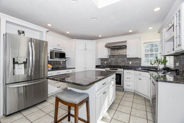 kitchen with white cabinetry, sink, stainless steel appliances, tasteful backsplash, and a kitchen island