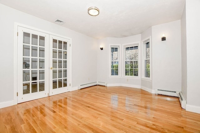 empty room with french doors, hardwood / wood-style flooring, and a baseboard heating unit