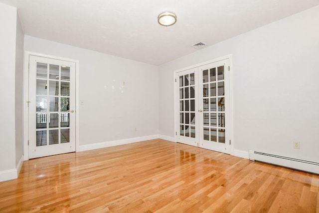 unfurnished room with wood-type flooring, baseboard heating, and french doors