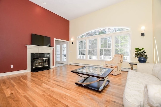 living room featuring light wood-type flooring, baseboard heating, and a towering ceiling