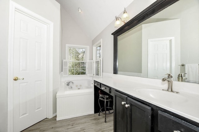 bathroom featuring tiled bath, vanity, lofted ceiling, and hardwood / wood-style flooring