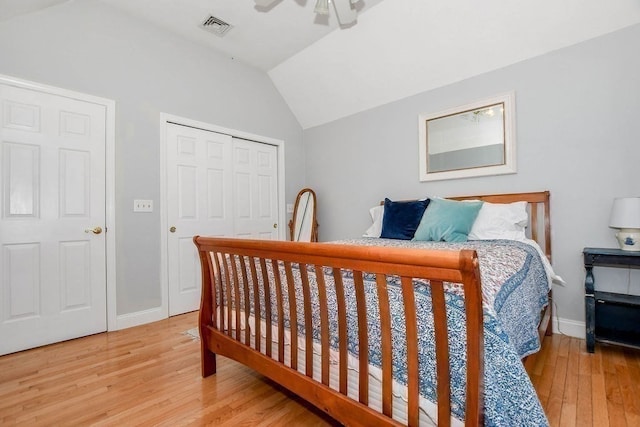 bedroom featuring ceiling fan, light hardwood / wood-style floors, lofted ceiling, and a closet