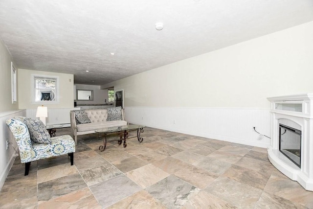 4 Olde Logging Rd, Marion, MA 02738 - living area with a wainscoted wall, a glass covered fireplace, and light stone finish floors