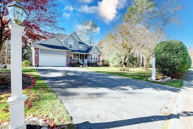 4 Olde Logging Rd, Marion, MA 02738 - view of front of property featuring asphalt driveway, an attached garage, covered porch, brick siding, and a front lawn