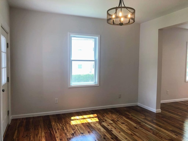 28-32 Calvary St, Waltham, MA 02453 - empty room with dark wood-style floors, baseboards, and an inviting chandelier