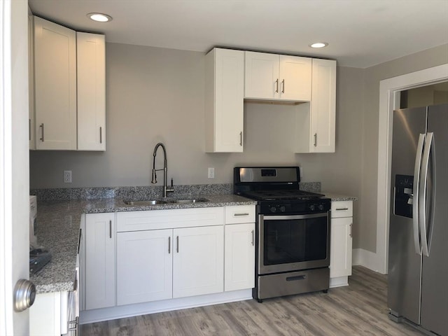 28-32 Calvary St, Waltham, MA 02453 - kitchen with light wood finished floors, appliances with stainless steel finishes, stone countertops, white cabinetry, and a sink