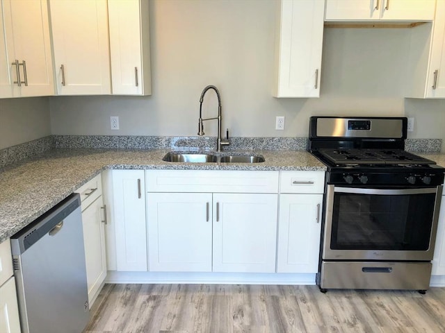 28-32 Calvary St, Waltham, MA 02453 - kitchen featuring light stone counters, stainless steel appliances, white cabinetry, a sink, and light wood-type flooring