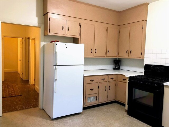 28-32 Calvary St, Waltham, MA 02453 - kitchen with freestanding refrigerator, backsplash, light countertops, and black gas range oven