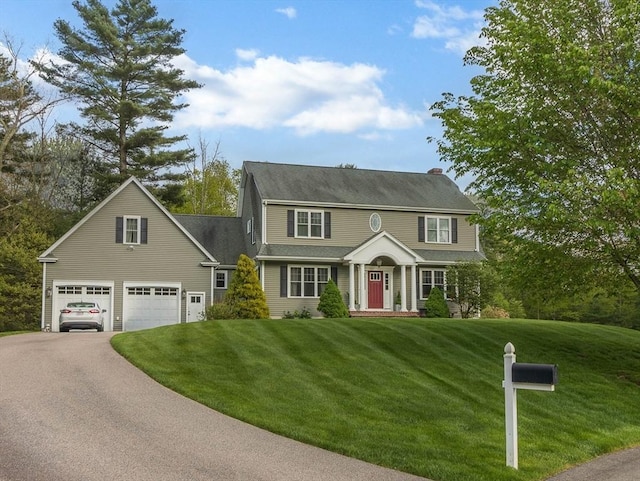 view of front of house with driveway, a garage, a front yard, and a chimney