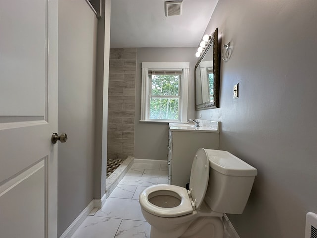 bathroom with vanity, toilet, and tiled shower