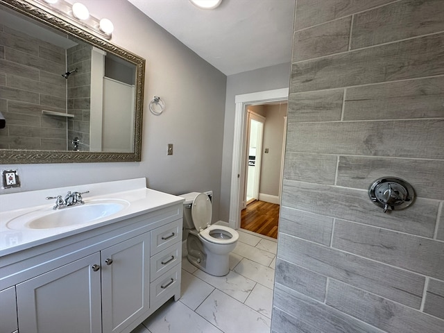 bathroom with vanity, toilet, wood-type flooring, and tiled shower