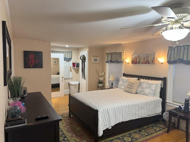 bedroom with ensuite bath, a ceiling fan, crown molding, and wood finished floors