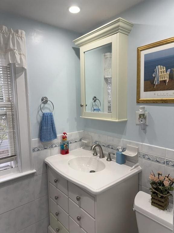 bathroom featuring toilet, tile walls, recessed lighting, vanity, and a wainscoted wall