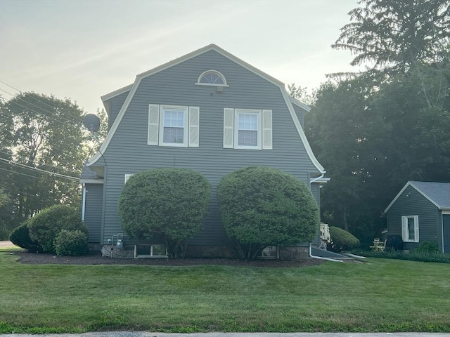 view of property exterior with a gambrel roof and a yard