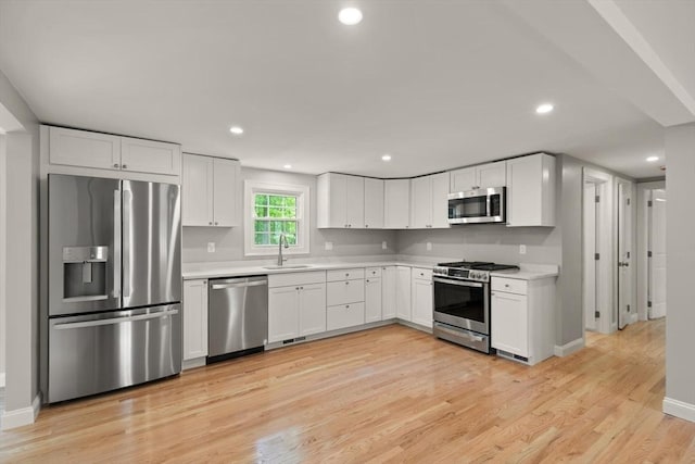 7 Chestnut St, West Newbury, MA 01985 - kitchen with stainless steel appliances, a sink, light countertops, light wood-style flooring, and white cabinets