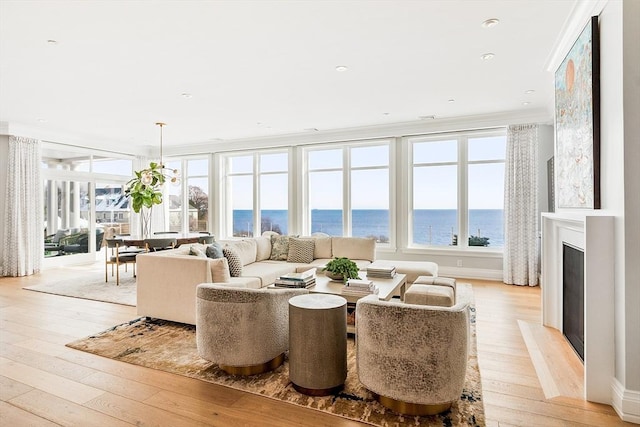 living room with a water view, a healthy amount of sunlight, and light hardwood / wood-style flooring