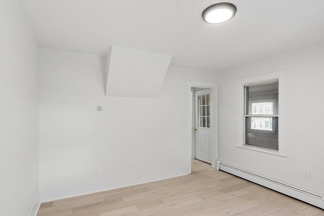 spare room featuring a baseboard heating unit and light wood-type flooring