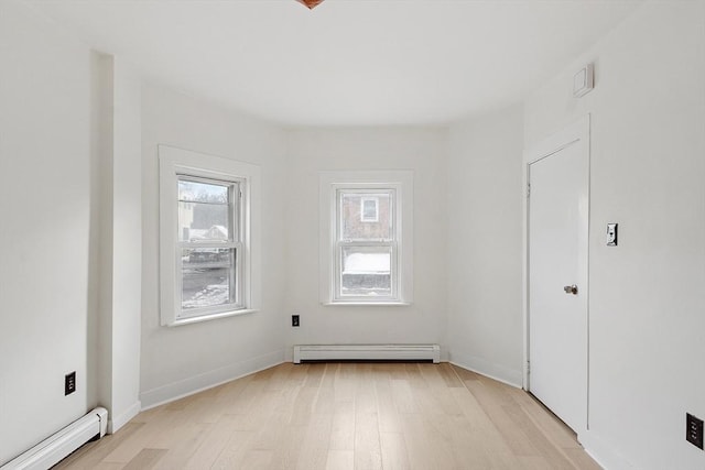 empty room with light hardwood / wood-style flooring and baseboard heating