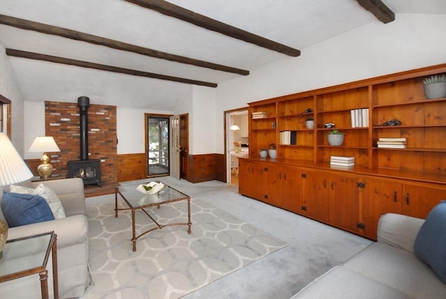 living room featuring vaulted ceiling with beams, light colored carpet, wood walls, wainscoting, and a wood stove