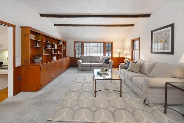 living room featuring a wainscoted wall, light colored carpet, and vaulted ceiling with beams