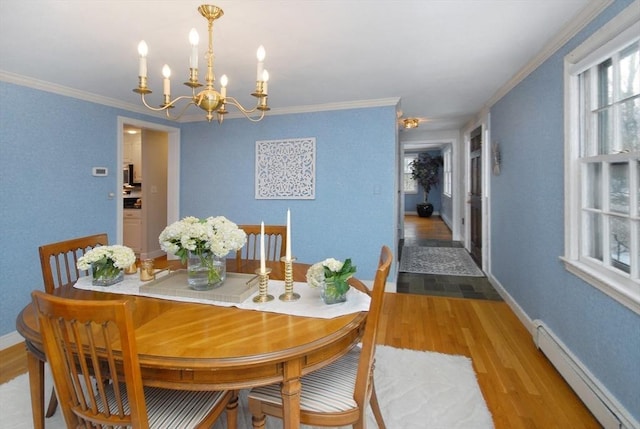 dining room with a baseboard heating unit, crown molding, light wood-style floors, and baseboards