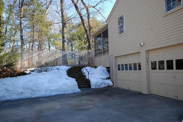 view of home's exterior with driveway, stairway, fence, and a sunroom