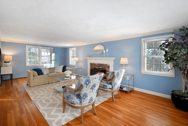 living room featuring crown molding, a fireplace, baseboards, and wood finished floors