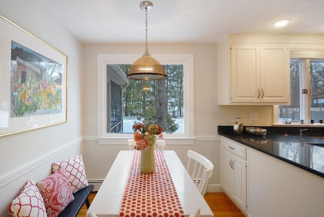 interior space featuring hanging light fixtures, baseboard heating, dark countertops, and white cabinets