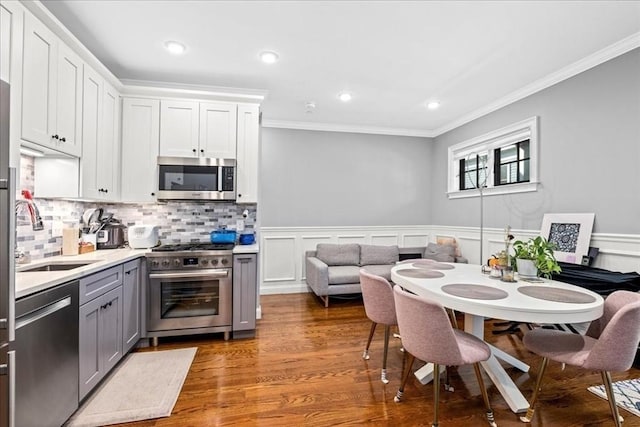 kitchen with appliances with stainless steel finishes, a sink, gray cabinetry, ornamental molding, and light countertops