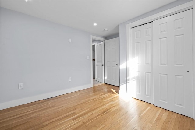 unfurnished bedroom featuring light wood-type flooring and a closet