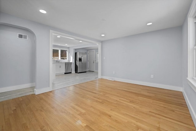 unfurnished living room featuring sink and light hardwood / wood-style flooring