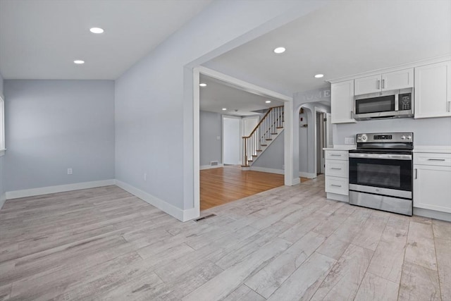 kitchen featuring stainless steel appliances, white cabinetry, and light hardwood / wood-style flooring