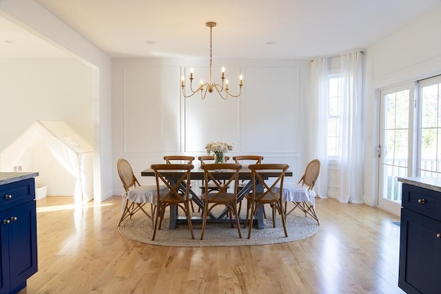 dining area with a decorative wall, light wood-style floors, and an inviting chandelier