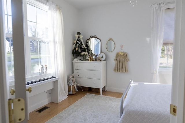 bedroom with light wood finished floors, visible vents, and baseboards