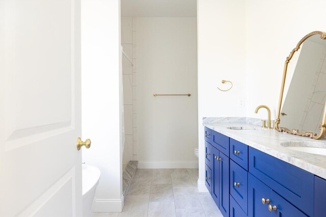 bathroom with a sink, toilet, double vanity, and baseboards