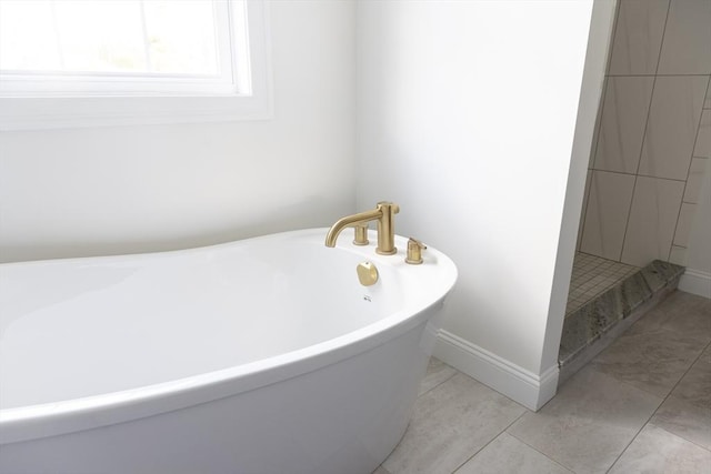 bathroom featuring tile patterned floors, a freestanding bath, and baseboards