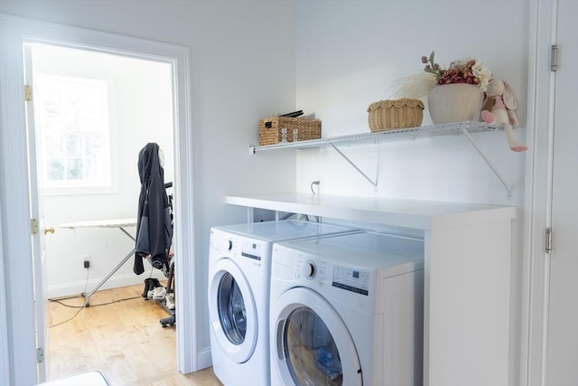 washroom featuring washer and dryer, laundry area, light wood finished floors, and baseboards