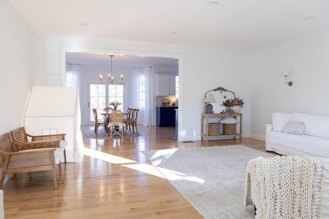 living room with light wood-style flooring, an inviting chandelier, and baseboards