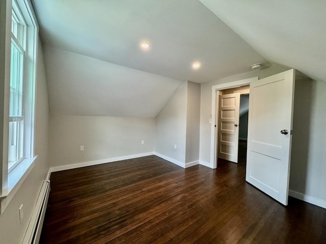 bonus room with a baseboard heating unit, dark hardwood / wood-style floors, a healthy amount of sunlight, and vaulted ceiling