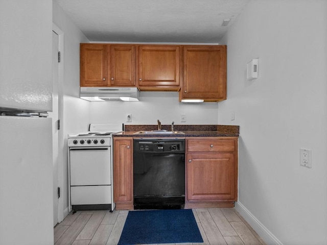 kitchen featuring white appliances, brown cabinetry, under cabinet range hood, and a sink