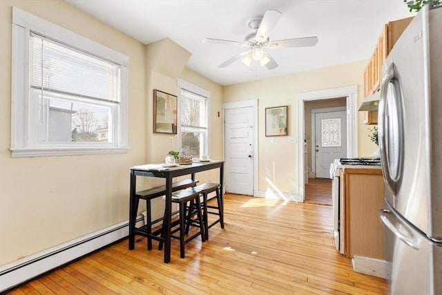 dining space featuring a wealth of natural light, light wood-type flooring, ceiling fan, and baseboards