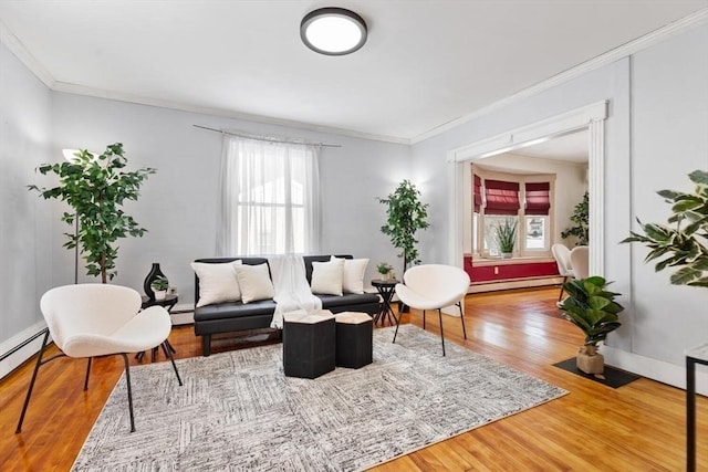 living area featuring ornamental molding, a wealth of natural light, baseboard heating, and wood finished floors