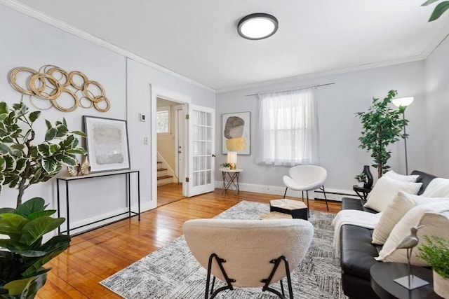 living room featuring a baseboard heating unit, wood finished floors, baseboards, french doors, and crown molding