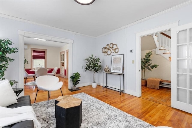 living area featuring light wood-style flooring, stairs, ornamental molding, and baseboards