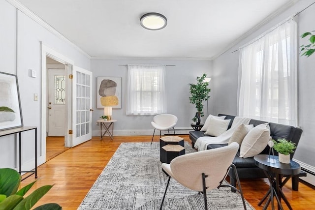 living room featuring ornamental molding, a baseboard radiator, baseboards, and wood finished floors