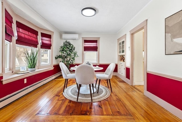 dining room with a baseboard heating unit, baseboards, a wall unit AC, and hardwood / wood-style floors