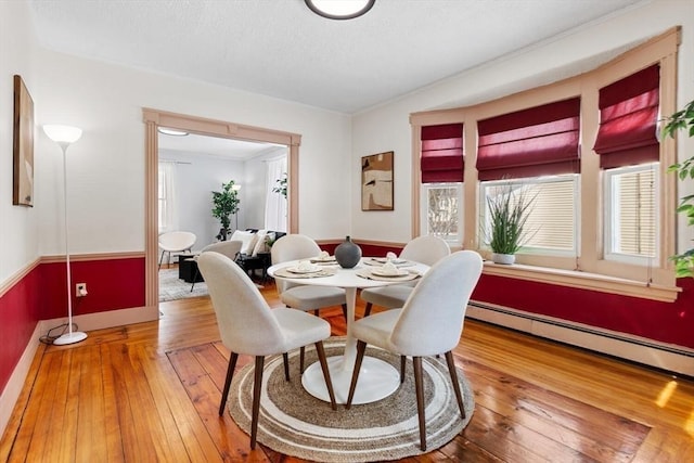 dining area featuring a textured ceiling, hardwood / wood-style floors, and baseboard heating