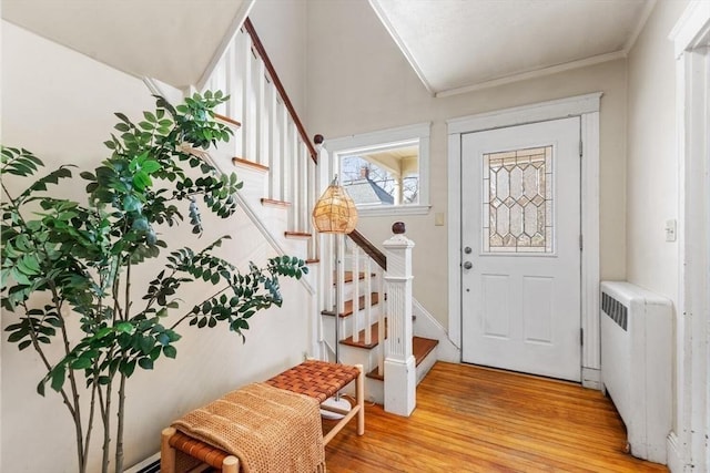 foyer with light wood-style floors, stairway, and radiator heating unit